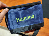 Blue pouch with 'Humana' logo held by a hand on a wooden surface
