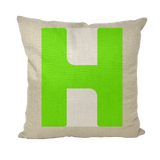 A square-shaped throw pillow with a green text 'H' on a beige background.